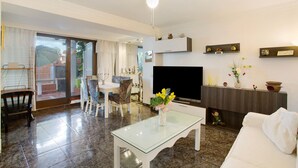 Un salon avec une table basse en verre, un canapé blanc, un téléviseur et un ventilateur de plafond.