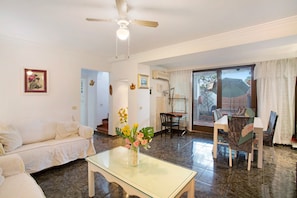 A living room with a glass coffee table, a white sofa, a dining table with chairs, and a ceiling fan. - Semi-Detached Bungalow 'La Casa De Ramón' with Sea View, Wi-Fi and Air Conditioning (Mogán)
