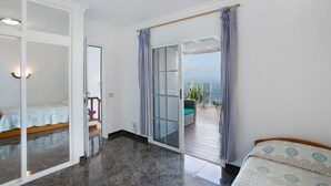 Une chambre avec un lit, une salle de bain avec des toilettes et un balcon avec vue.