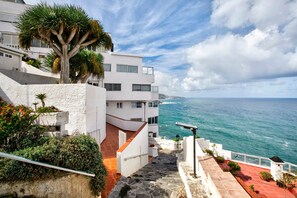 A coastal building with a staircase leading to a balcony overlooking the sea.