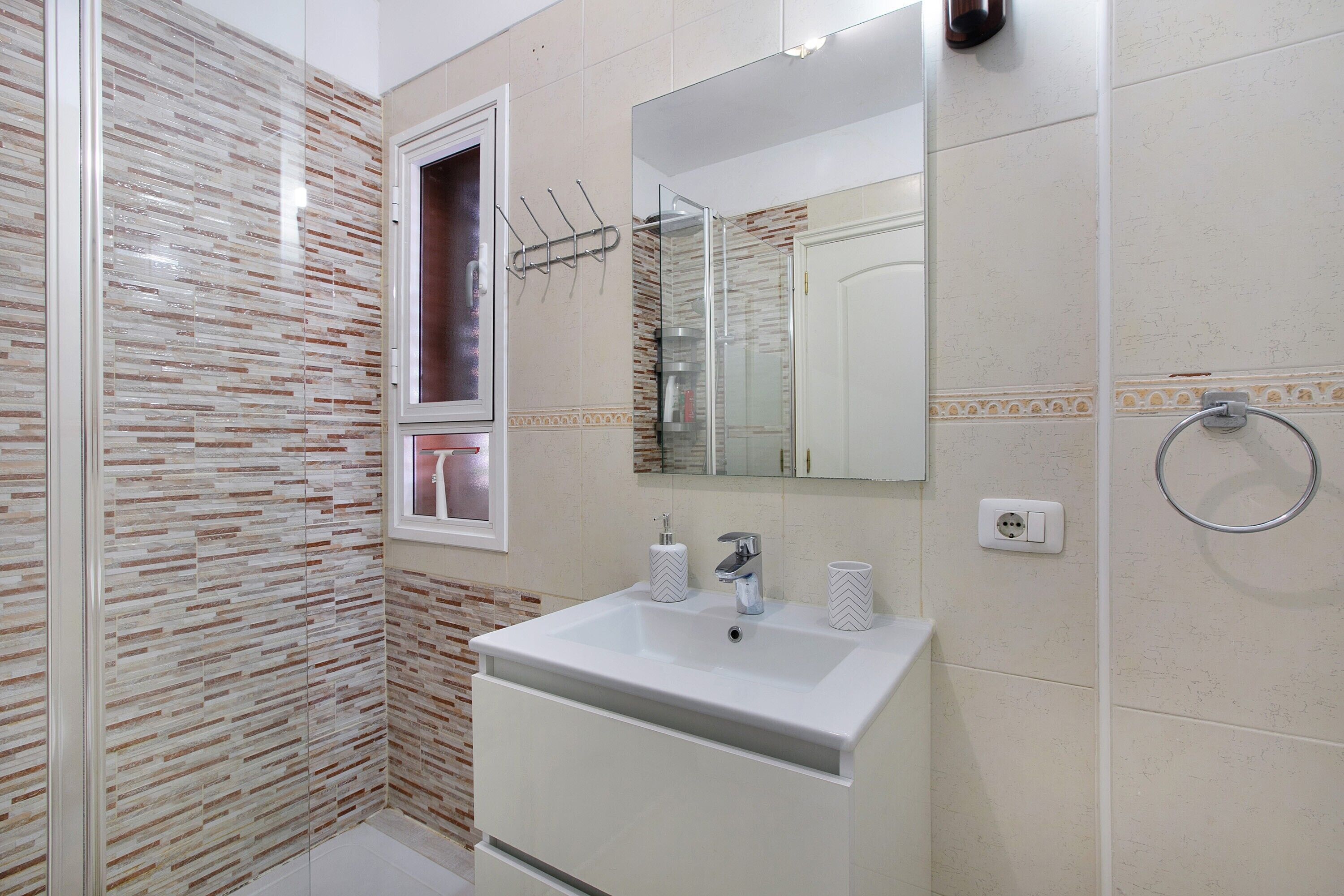 Une salle de bain avec une douche à parois de verre, un lavabo avec un miroir et un porte-serviettes.