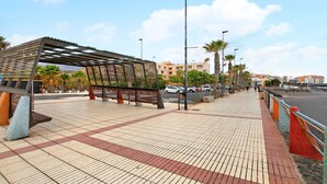 A pedestrian walkway with a wooden shelter, benches, and palm trees. - Vacation Apartment 'Beach Front Puertito' with Shared Pool, Private Terrace and Wi-Fi (Güimar)