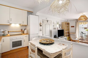 A kitchen with white cabinets, a stove, and a dining table with a decorative plate.