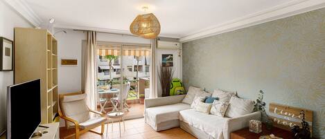 A living room with a TV, a wooden chair, a sofa, and a coffee table with decorative items.