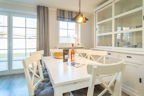 A dining area with a white table, chairs, and a hanging light fixture. - Appartement Lachmöwe (Wenningstedt-Braderup (Sylt))