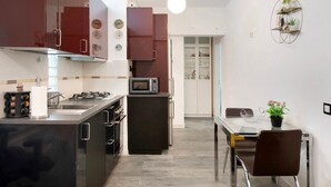 Una cocina moderna con electrodomésticos de acero inoxidable, un comedor con mesa de vidrio y vista al comedor contiguo.