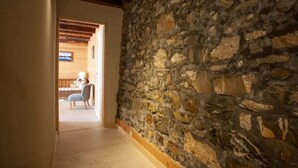 A stone wall corridor with a wooden floor, a chair, and a wooden ceiling beam. - Chalet 'L'Échappée Des Rêves' with Mountain View, Private Terrace and Wi-Fi (Verchaix)