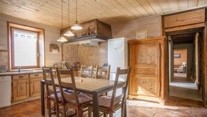 A wooden interior with a dining table, chairs, a kitchen area, and a view into another room. - Chalet 'L'Échappée Des Rêves' with Mountain View, Private Terrace and Wi-Fi (Verchaix)