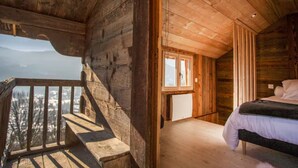 A wooden cabin with a balcony, a bed, and a view of the mountains. - Chalet 'L'Échappée Des Rêves' with Mountain View, Private Terrace and Wi-Fi (Verchaix)