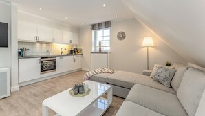 A modern apartment with a kitchen, living area, and a dining table. - Appartement Dünenglück (Wenningstedt-Braderup (Sylt))