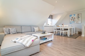Uma sala de estar moderna com sofá, mesa de centro e área de jantar.
