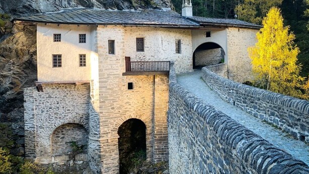 A stone building with a balcony, arched windows, and a stone wall. - Apartment 'Le Petit Bonheur' with Mountain View and Balcony (Modane)