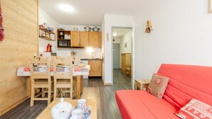 A compact living space with a kitchen, dining area, and a red sofa. - Apartment 'Le Petit Bonheur' with Mountain View and Balcony (Modane)
