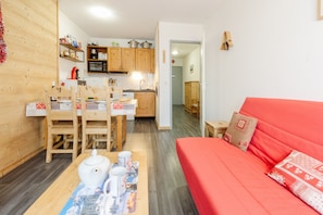 A compact living space with a kitchen, dining area, and a red sofa. - Apartment 'Le Petit Bonheur' with Mountain View and Balcony (Modane)