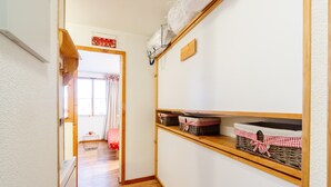 Un couloir étroit avec un plancher en bois, un mur blanc et des étagères garnies de paniers.