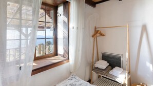 A bedroom with a bed, a window with curtains, a wooden ceiling, and a bedside table with towels. - Holiday Home 'Media Pipa' with Sea View, Wi-Fi and Air Conditioning (Puntagorda)
