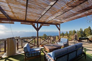 Ein überdachter Außenbereich mit Holzmöbeln und Blick auf die Landschaft.
