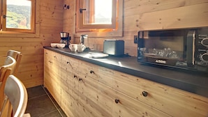 Een houten interieur met een keukentoog, een koffiezetapparaat, een broodrooster en een magnetron.