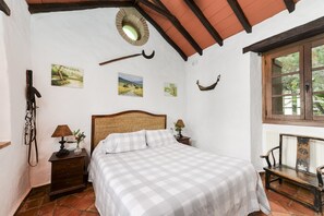 Un dormitorio con una colcha a cuadros, cabecera de madera, mesita de noche con lámpara y cuadros en la pared.