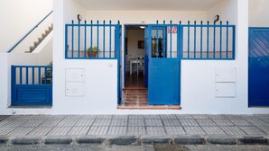 A white building with a blue gate, a staircase, and a tiled entrance. - Holiday Home 'Casa Famara' with Sea Views, Private Terrace and Wi-Fi (Caleta de Famara)
