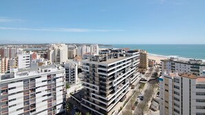 Um edifício alto com várias varandas, vista para a praia e céu claro.
