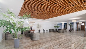 Um hall amplo com teto de madeira, plantas em vasos e uma placa com o nome 'TARIK'.