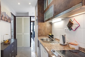 A modern kitchen with a stainless steel sink, a kettle, and a stove.