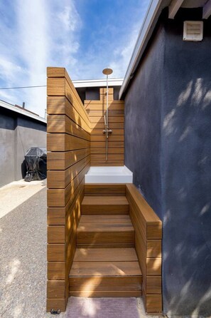 A small wooden outdoor shower with a metal showerhead, steps leading up to it, and a blue wall on one side. - The Succulent House, parking, walk to Bay! (San Diego)