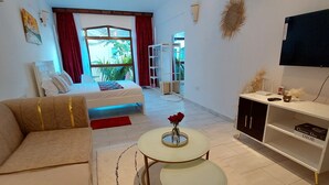 A modern living room with a sofa, two round tables, a bookshelf, and a TV. - Diani Beach (Kwale)
