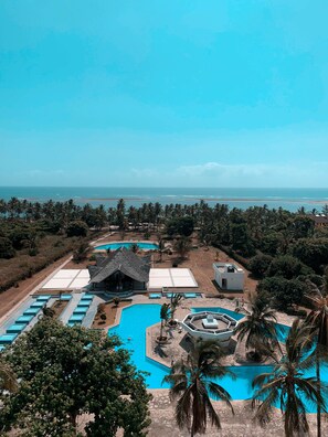 Um resort com várias piscinas, incluindo uma grande piscina central, e vista para o oceano.