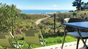 A patio with a table and chairs overlooking a coastal landscape.