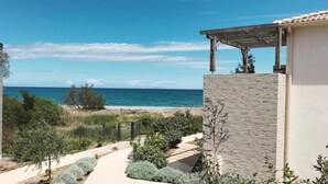 A coastal property with a view of the sea, a paved pathway, and a covered outdoor area.