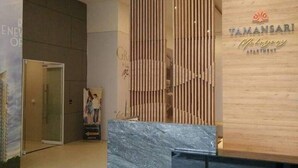 A reception area with a wooden panel wall, a marble counter, and a sign for 'Tamansari Apartment'.