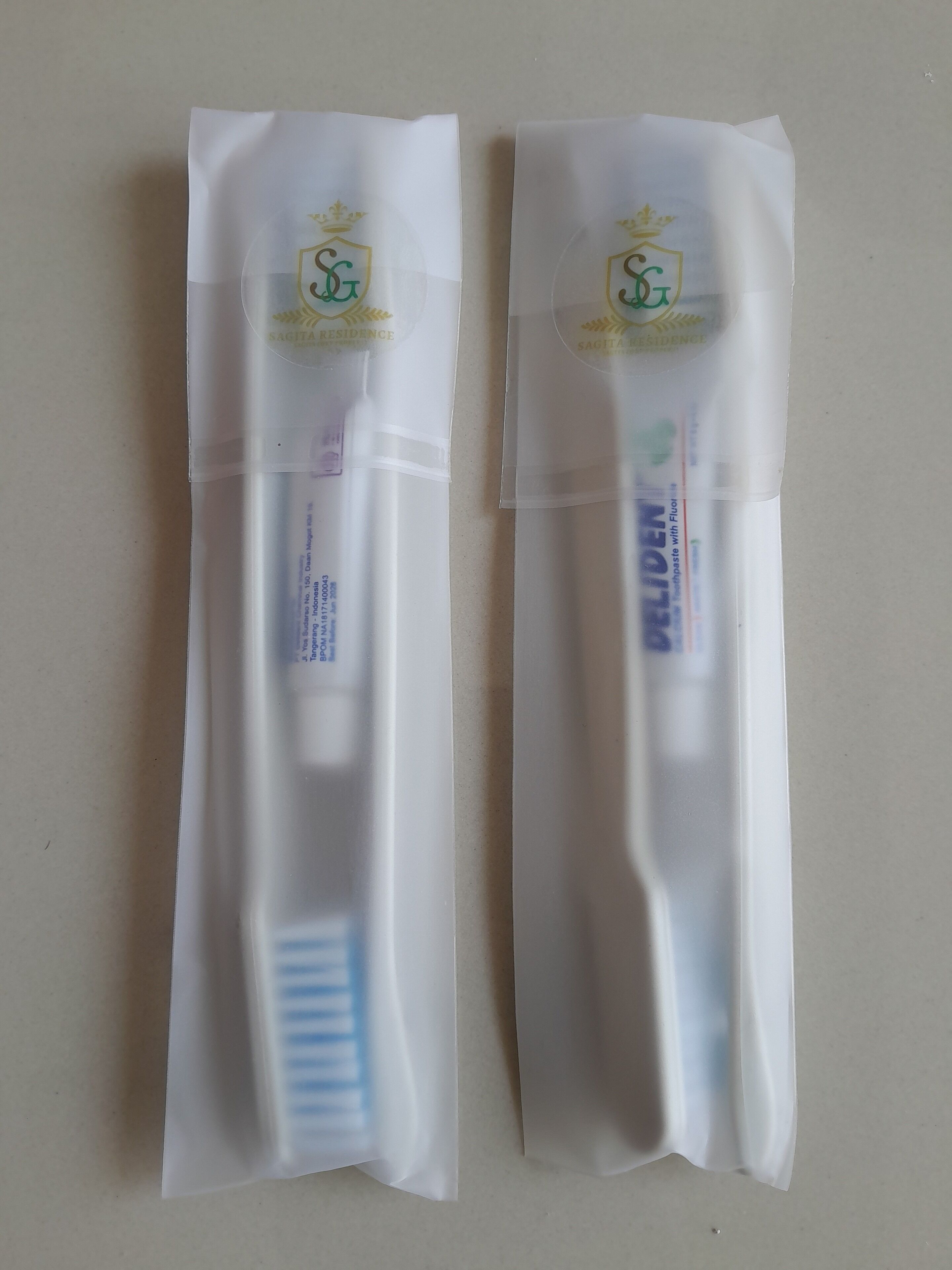 Zwei Zahnbürsten in transparenter Folienverpackung mit einem Logo und Text.