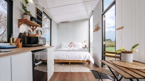 A modern bedroom with a wooden bed, a bedside table with a plant, and a view of the outdoors.