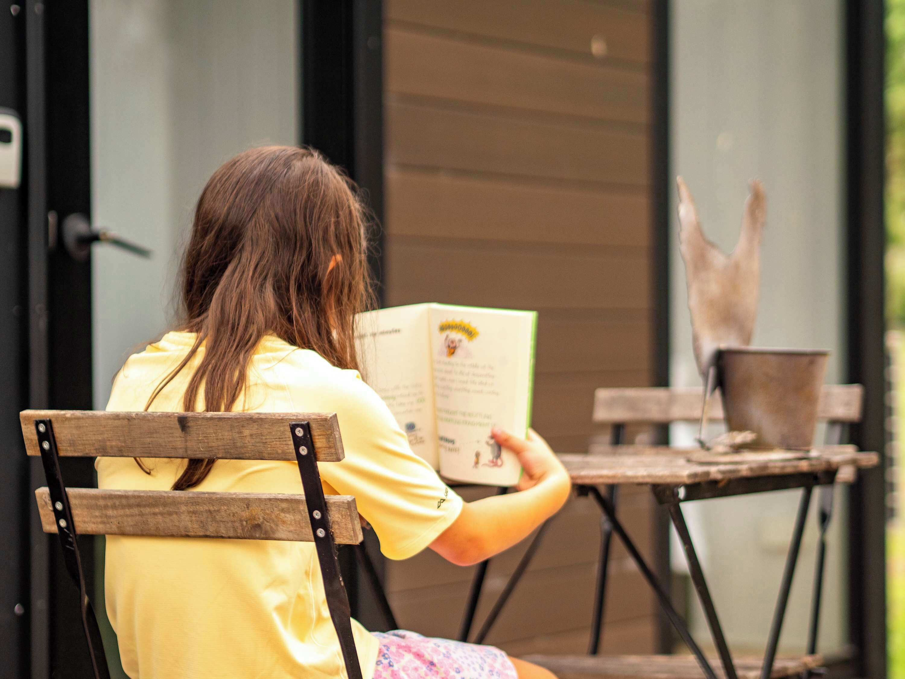 Una persona sentada en un banco de madera leyendo un libro.
