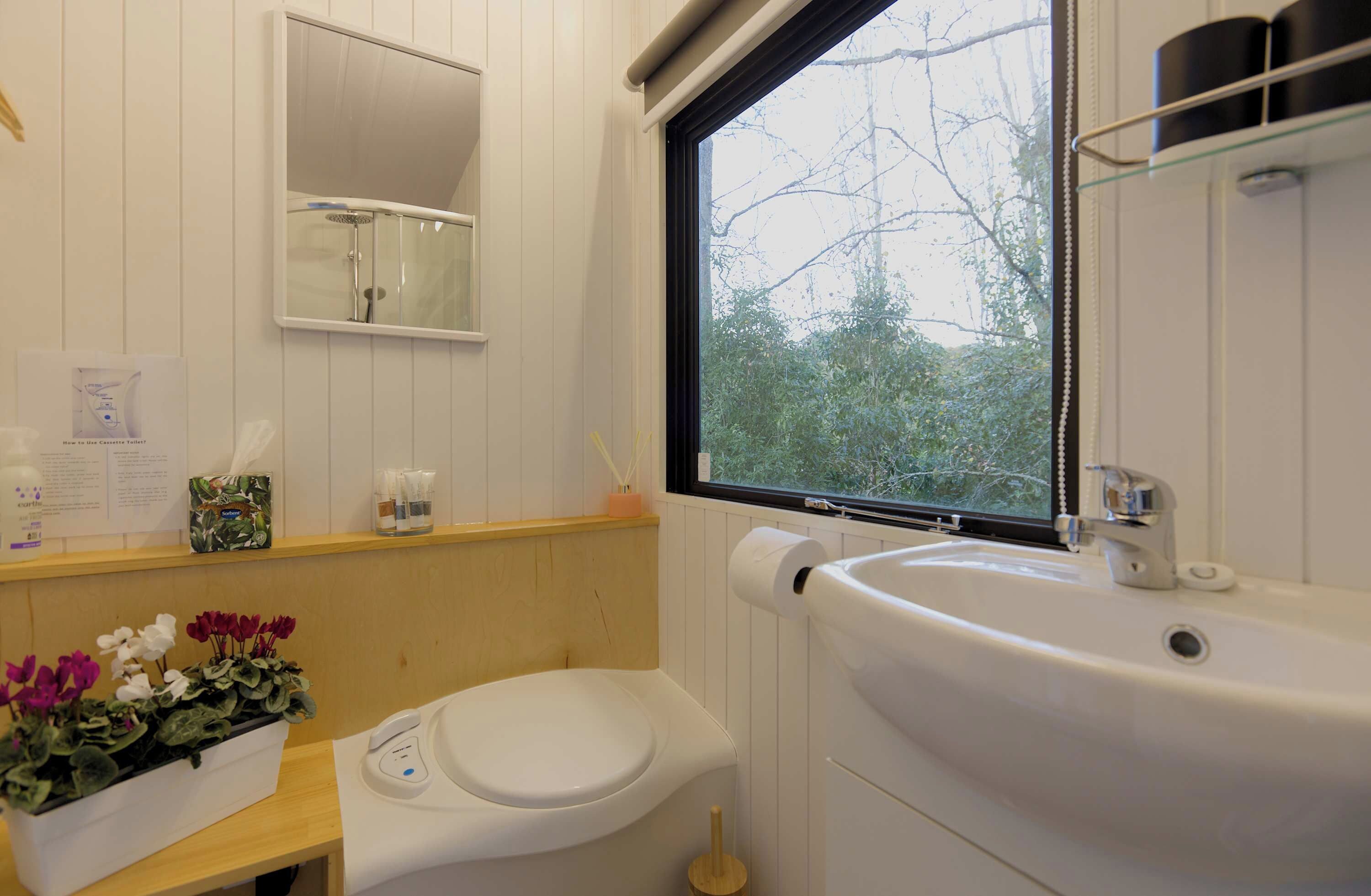 Une salle de bain avec des toilettes, un lavabo et une fenêtre.