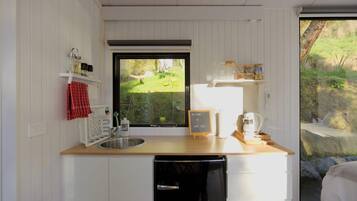 Een kleine keuken met een houten aanrecht, een spoelbak, een vaatwasser en een raam met uitzicht op een tuin.