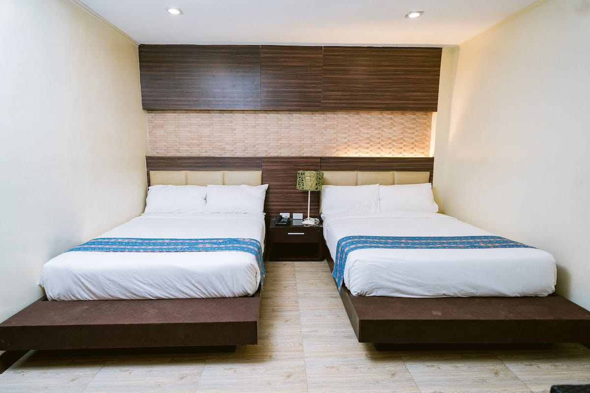 A double room with two beds, a wooden headboard, a nightstand, and a small table with a lamp.