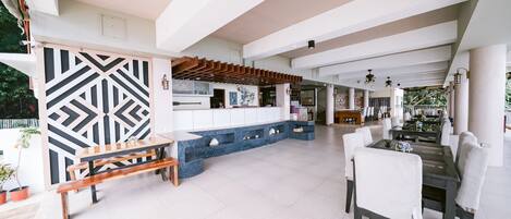 A spacious indoor area with a long bench, a dining table with chairs, and a blue tiled bench along the wall.