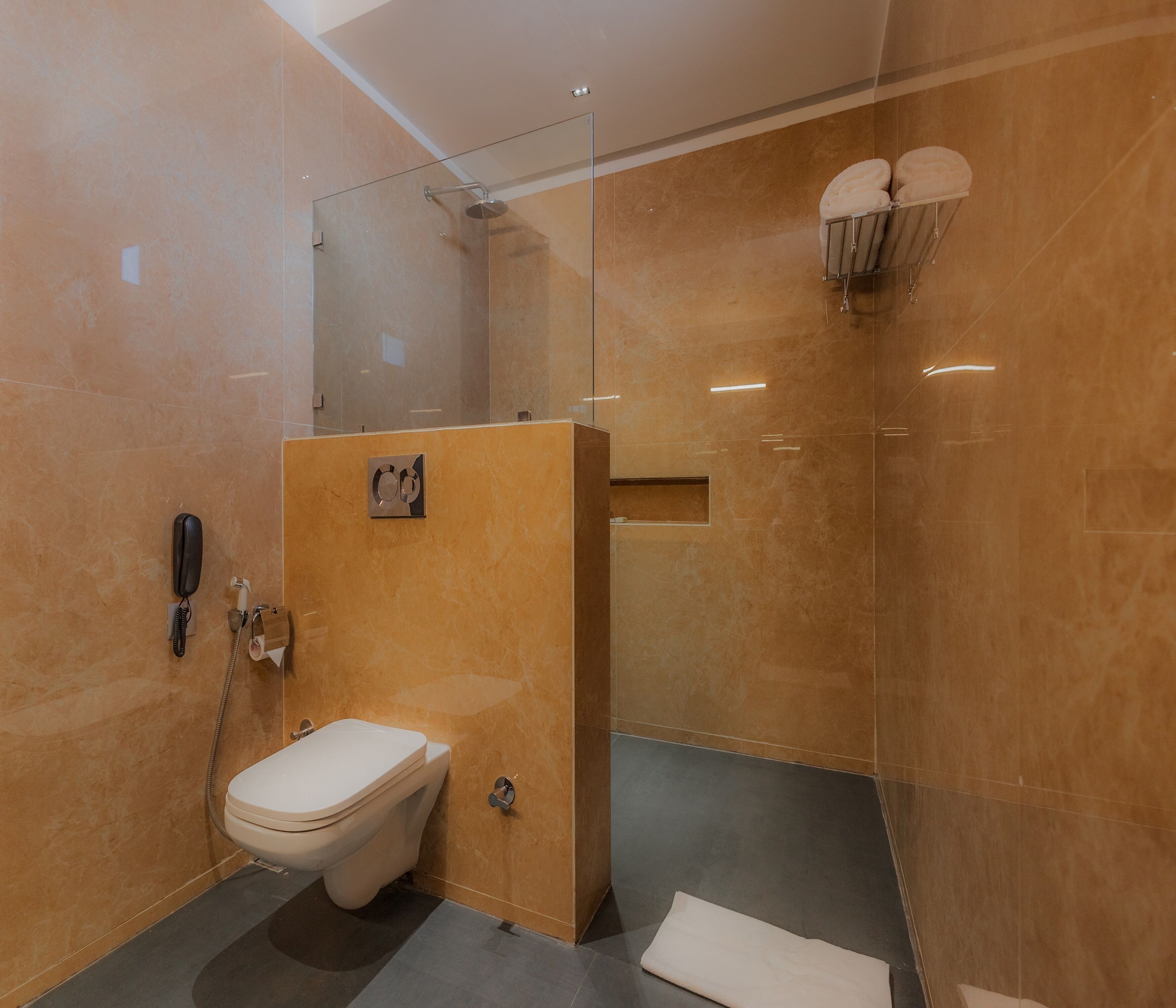 Een moderne badkamer met toilet, douche en een douchecabine met glazen wanden.