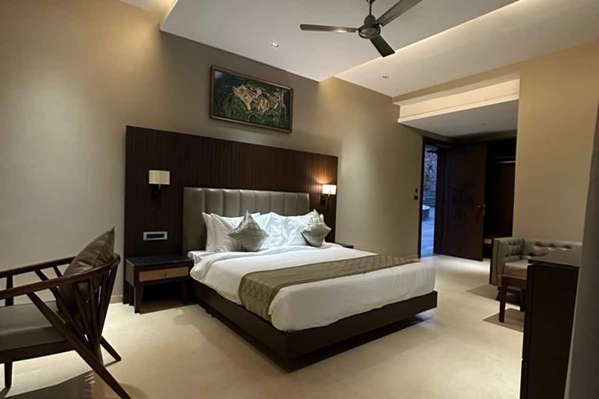 A modern bedroom with a large bed, a ceiling fan, and a painting on the wall.