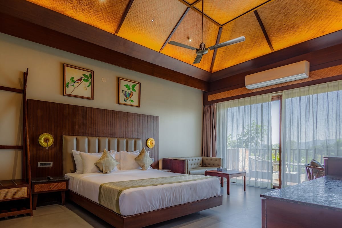 A spacious bedroom with a large bed, a ceiling fan, and a view of the outdoors through large windows.