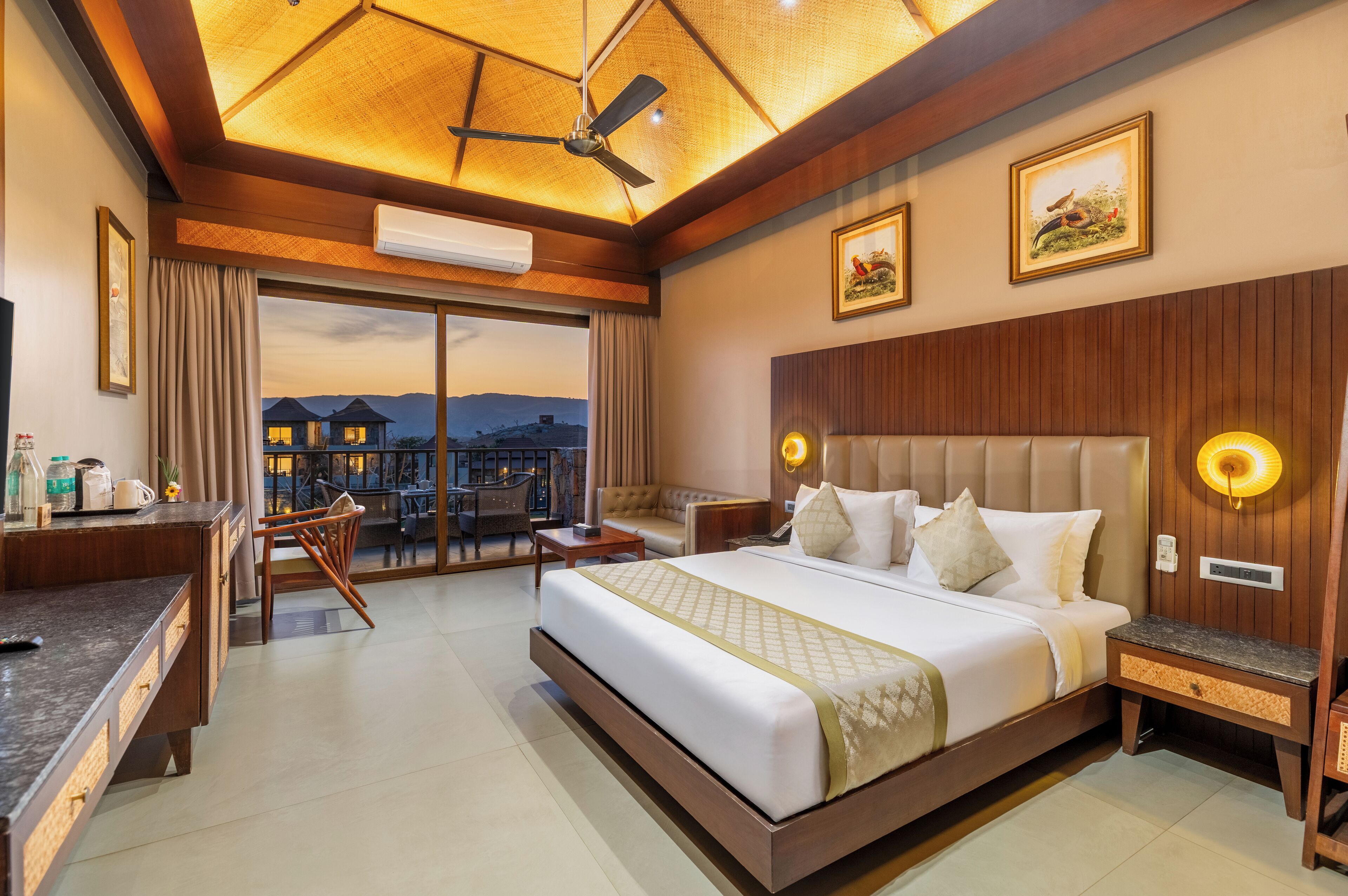 A hotel room with a large bed, a desk, a chair, and a view of mountains.