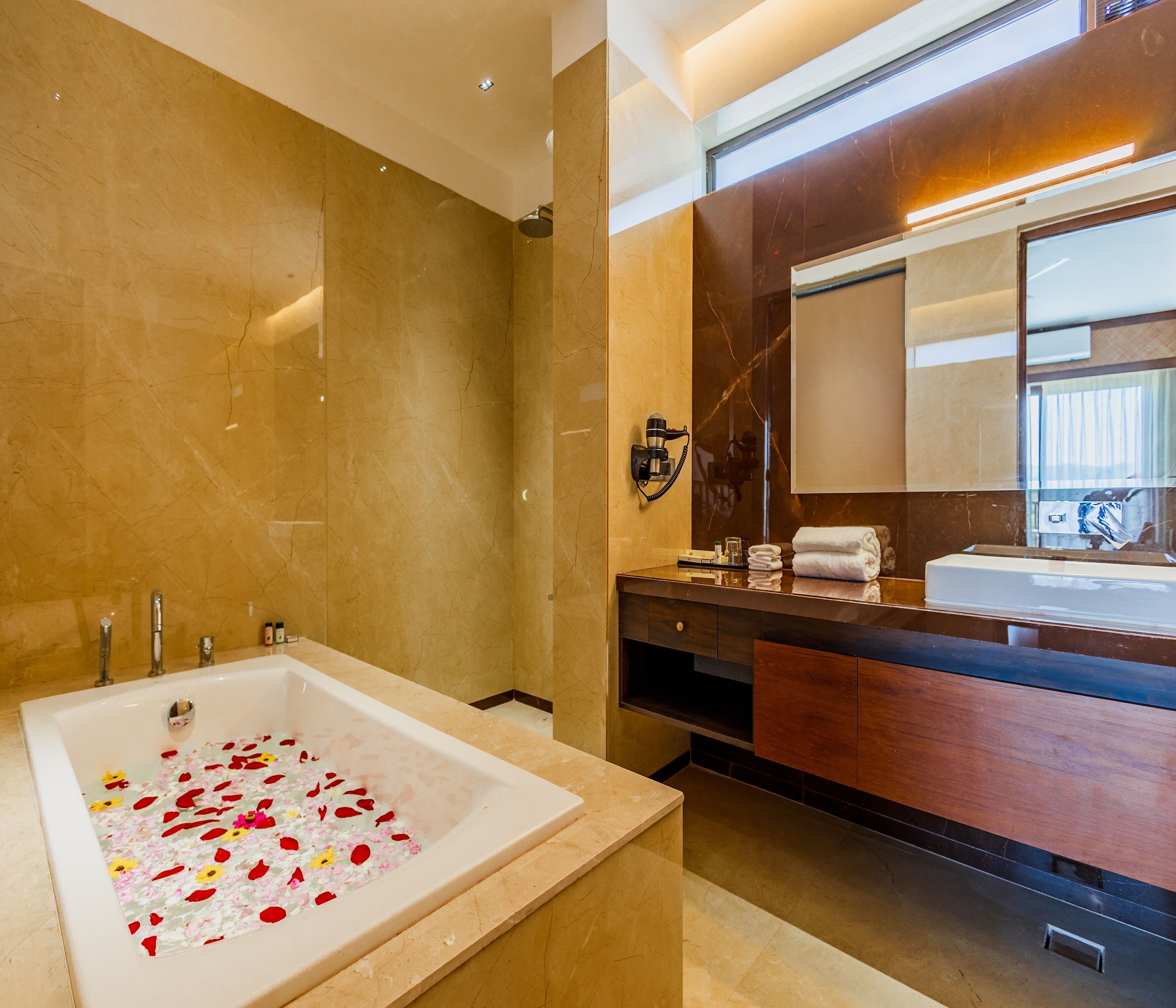 A modern bathroom with a large bathtub, a vanity with a mirror, and a shower area.