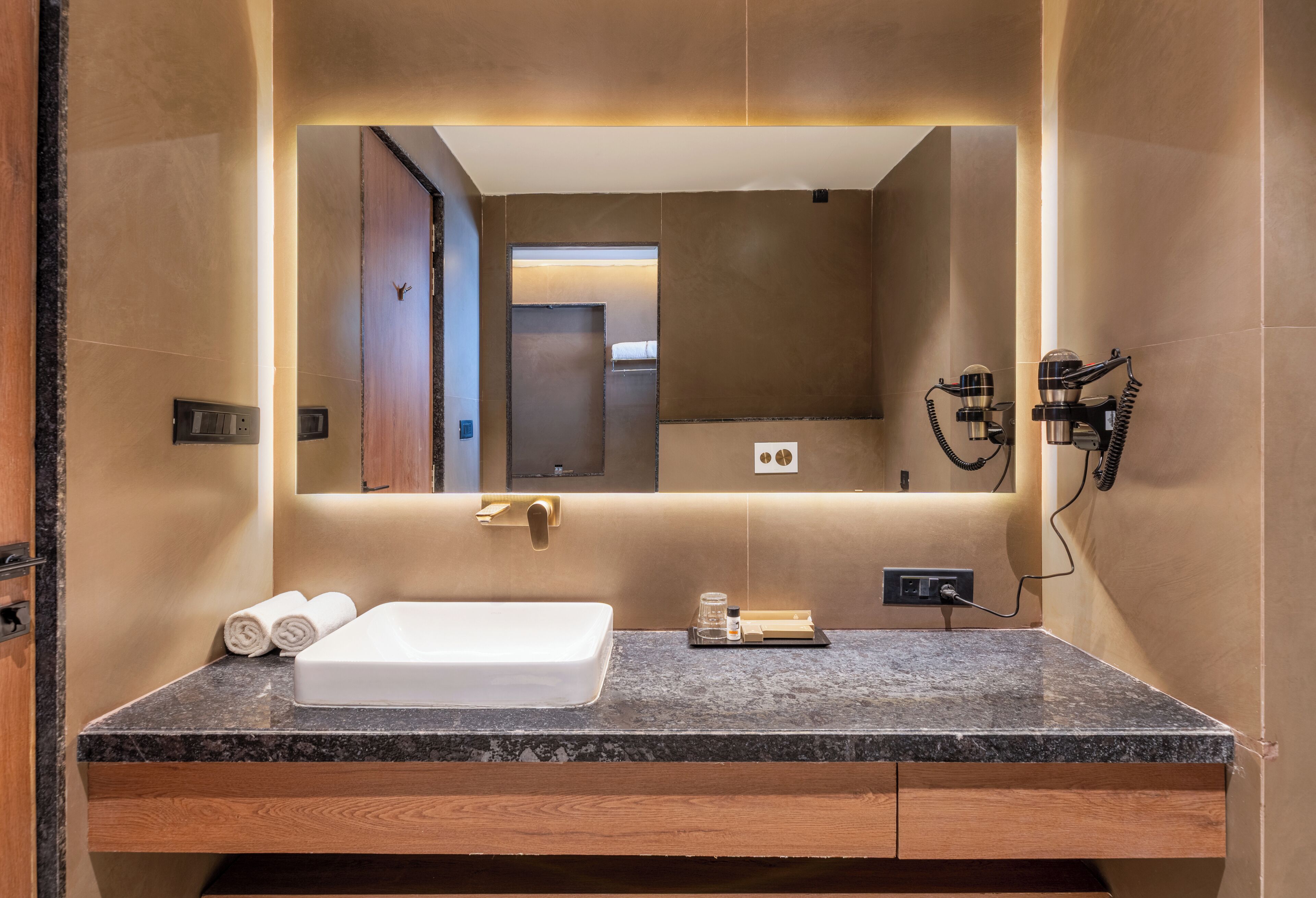 A modern bathroom with a large mirror, a built-in sink, and a vanity with a countertop.