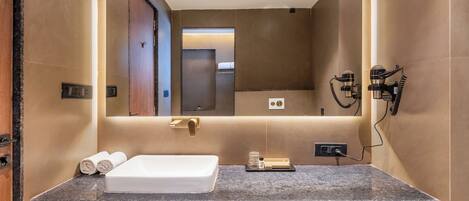 A modern bathroom with a large mirror, a built-in sink, and a vanity with a countertop.