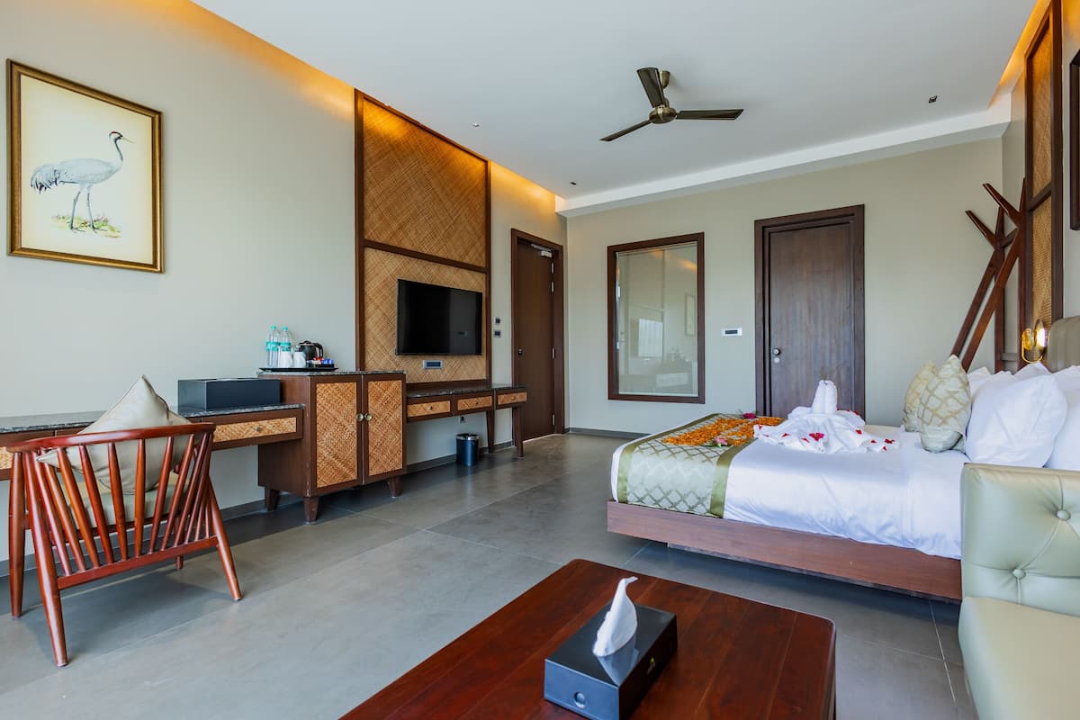 A hotel room with a bed, a desk, a television, and a ceiling fan.