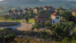 A residential area with multiple houses, a central building with a distinct roof, and a stone wall. - Sajjan Bagh Resort Kumbhalgarh (Kumbhalgarh)