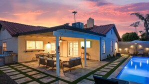 A house with a covered patio, a pool, and a well-lit outdoor area.